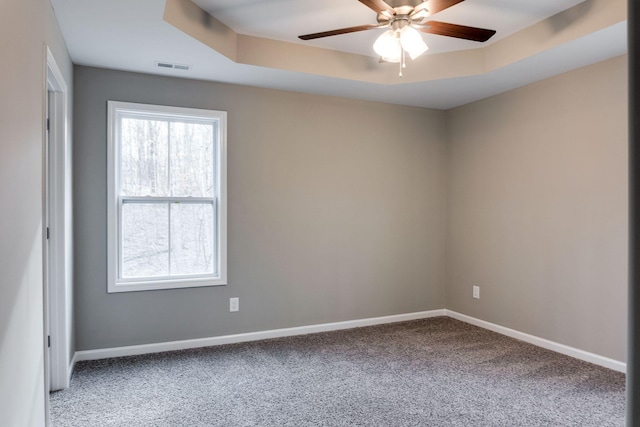 carpeted empty room featuring a tray ceiling and ceiling fan