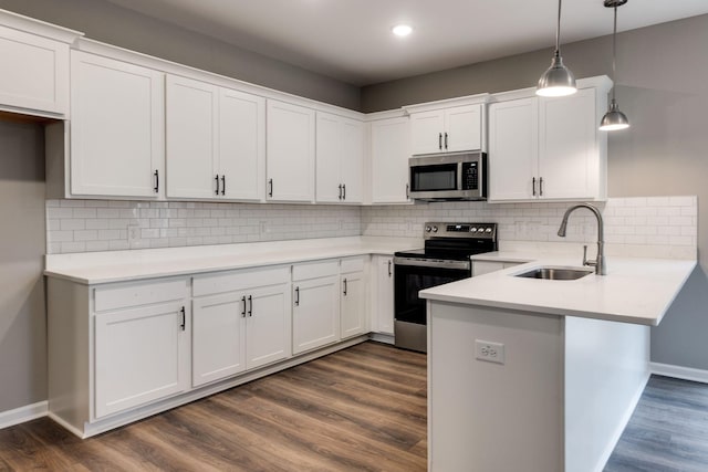 kitchen with white cabinetry, sink, hanging light fixtures, stainless steel appliances, and kitchen peninsula