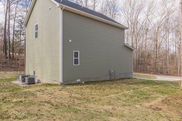 view of property exterior with central AC unit and a yard