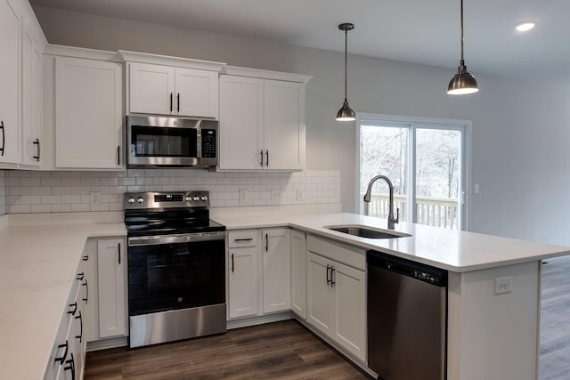 kitchen with kitchen peninsula, appliances with stainless steel finishes, sink, decorative light fixtures, and white cabinets