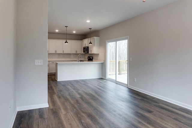 kitchen with pendant lighting, dark wood-type flooring, sink, kitchen peninsula, and white cabinetry