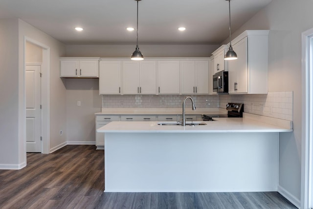 kitchen with black range with electric stovetop, sink, kitchen peninsula, pendant lighting, and white cabinets