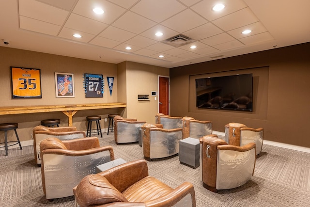 carpeted home theater room with a paneled ceiling