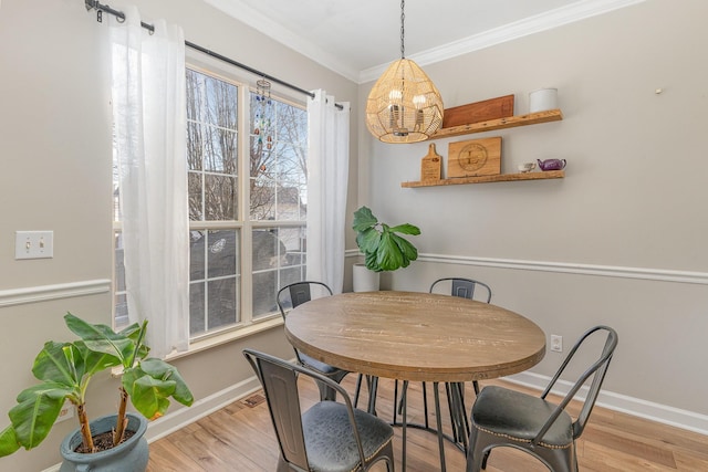 dining space featuring ornamental molding and light hardwood / wood-style flooring