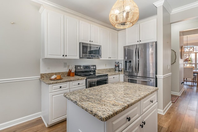 kitchen featuring stainless steel appliances, a center island, a notable chandelier, white cabinets, and decorative light fixtures