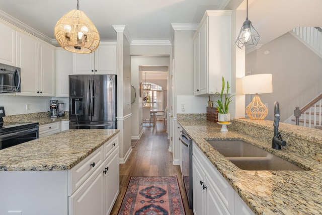 kitchen featuring appliances with stainless steel finishes, sink, white cabinets, and decorative light fixtures