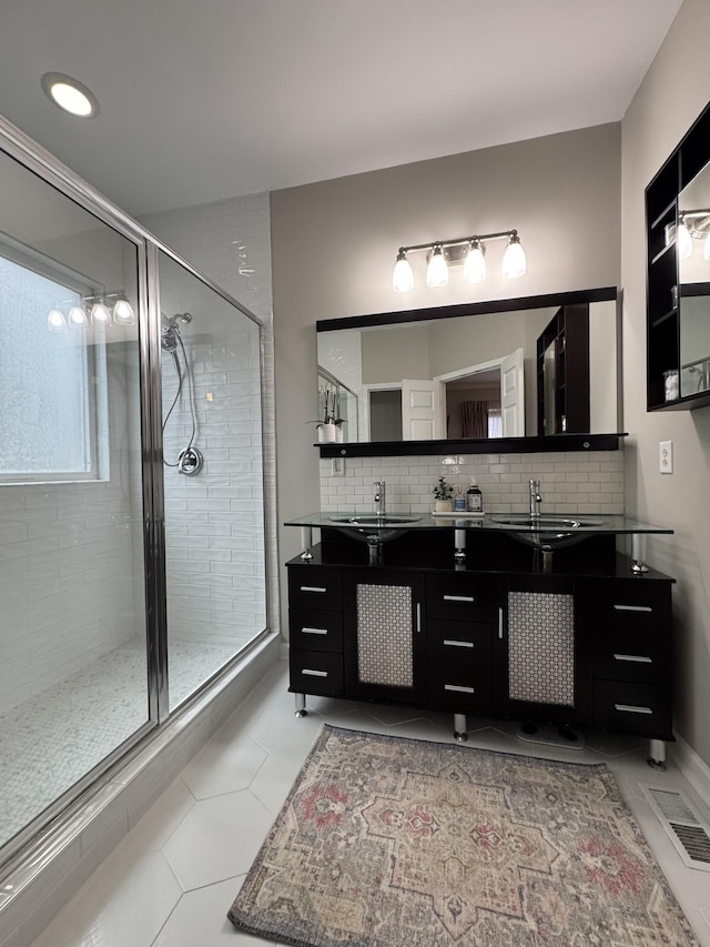 bathroom with vanity, decorative backsplash, and a shower with door