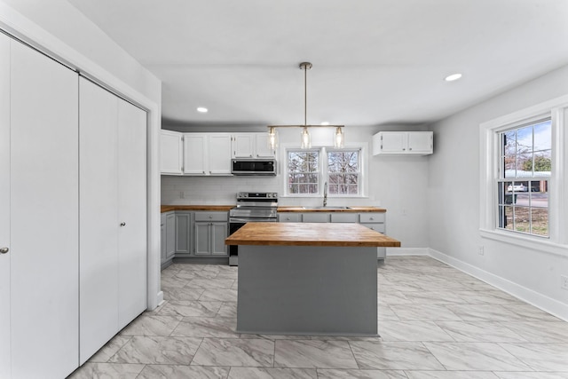 kitchen featuring pendant lighting, stainless steel appliances, wooden counters, white cabinets, and sink