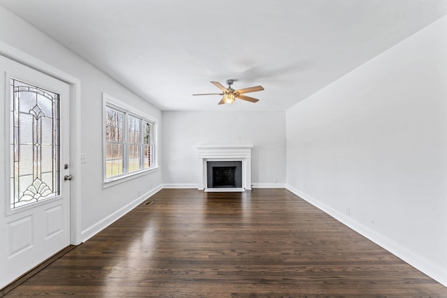 unfurnished living room featuring ceiling fan, dark wood-type flooring, and a fireplace