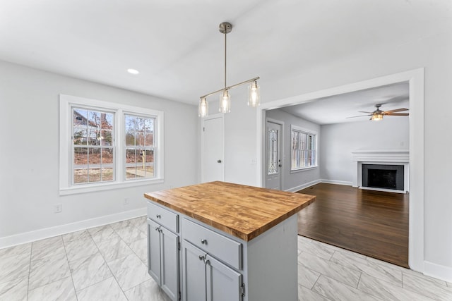 kitchen with pendant lighting, a kitchen island, a brick fireplace, wood counters, and plenty of natural light