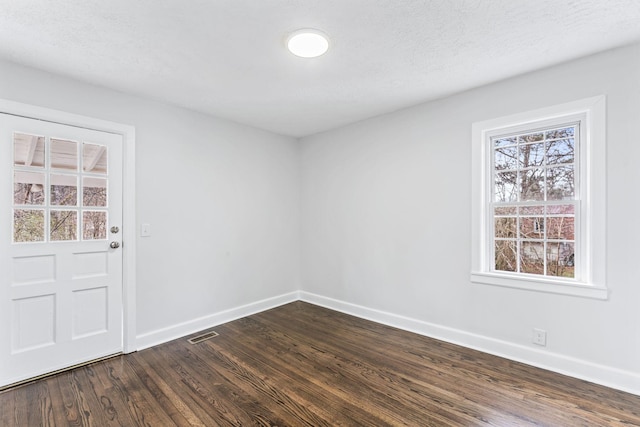 empty room featuring dark hardwood / wood-style flooring and a textured ceiling