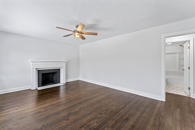 unfurnished living room with ceiling fan, a tile fireplace, and dark hardwood / wood-style floors