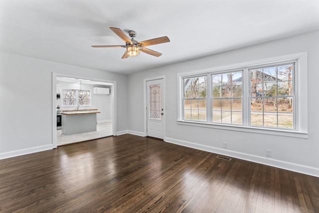 unfurnished living room with a wall unit AC, ceiling fan, and dark hardwood / wood-style flooring