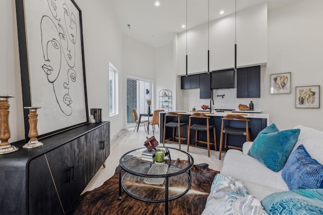 living room featuring light hardwood / wood-style floors, a towering ceiling, and sink