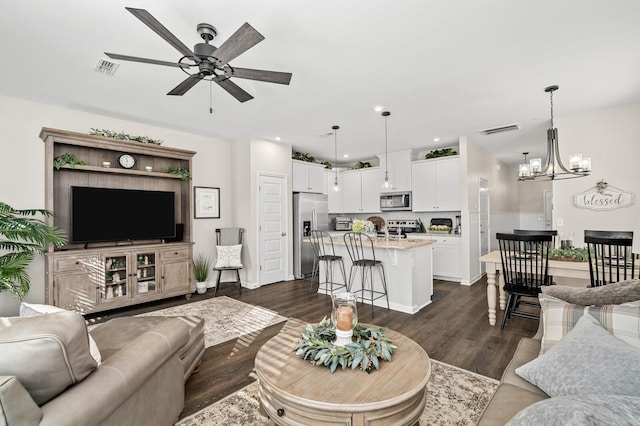 living room featuring ceiling fan with notable chandelier and dark hardwood / wood-style flooring