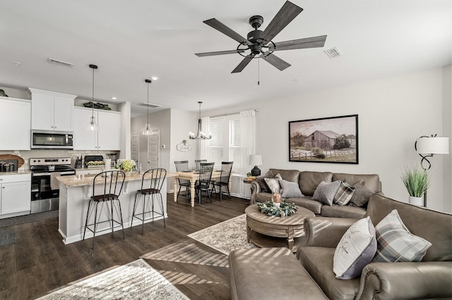 living room with dark wood-type flooring and ceiling fan with notable chandelier