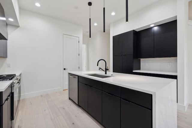 kitchen with a large island, sink, hanging light fixtures, light hardwood / wood-style floors, and appliances with stainless steel finishes