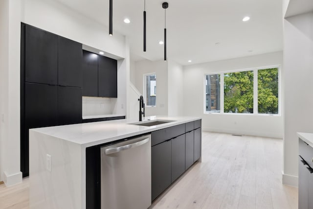 kitchen with sink, light hardwood / wood-style flooring, stainless steel dishwasher, a spacious island, and pendant lighting