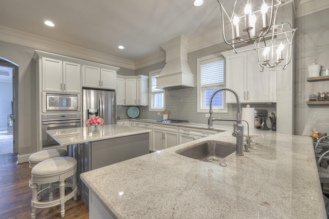 kitchen with a center island, a kitchen breakfast bar, light stone countertops, white cabinetry, and stainless steel appliances