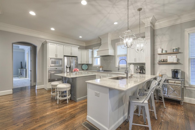 kitchen featuring a center island, white cabinets, custom range hood, a breakfast bar area, and stainless steel appliances