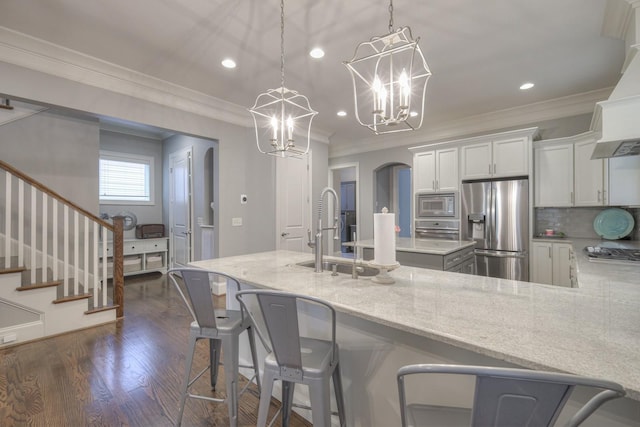 kitchen featuring light stone countertops, white cabinetry, stainless steel appliances, a chandelier, and decorative light fixtures