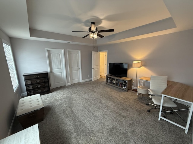 interior space featuring a raised ceiling, ceiling fan, and carpet