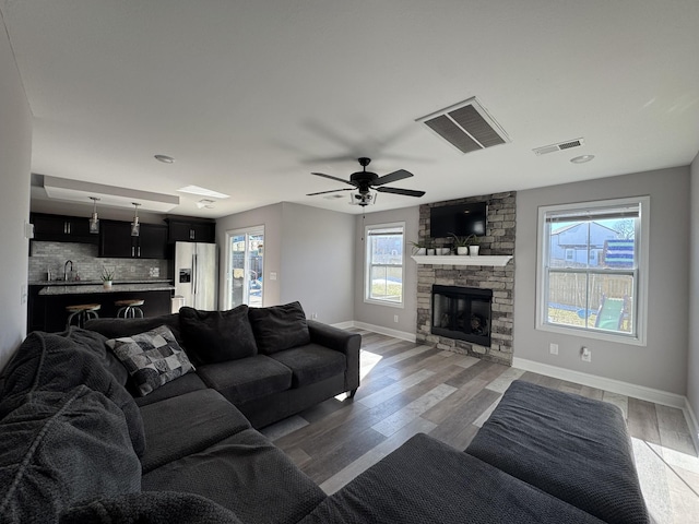 living room with ceiling fan, sink, a fireplace, and hardwood / wood-style floors