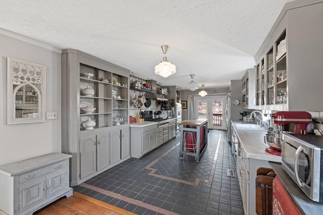 kitchen with stainless steel microwave, a sink, glass insert cabinets, gray cabinets, and open shelves