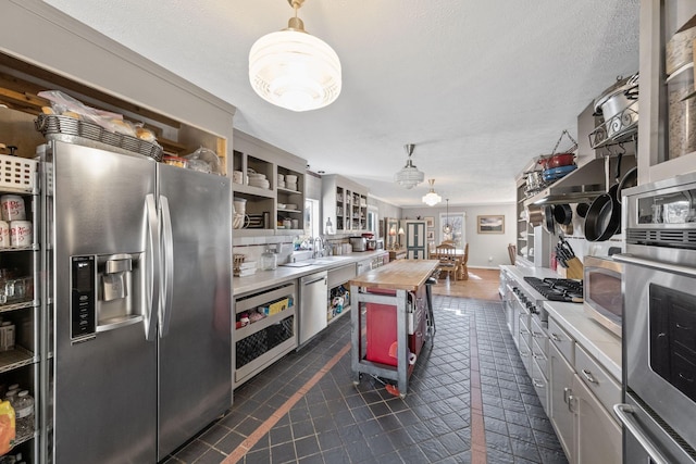 kitchen with appliances with stainless steel finishes, sink, butcher block countertops, and a textured ceiling