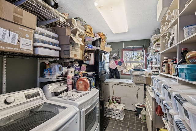 washroom featuring dark tile patterned floors, washing machine and dryer, and a textured ceiling