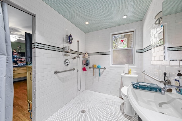 full bathroom featuring toilet, tiled shower, tile walls, and a sink