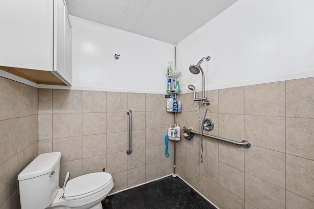 bathroom with tile walls, toilet, a tile shower, and a textured ceiling