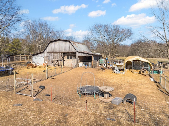 rear view of property featuring an outdoor structure and a trampoline