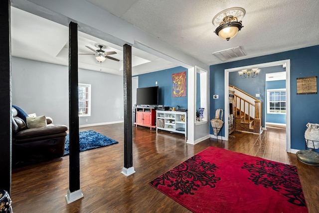 living room with dark hardwood / wood-style floors, a textured ceiling, and ceiling fan with notable chandelier