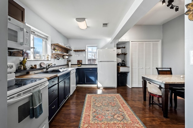 kitchen featuring sink, dark wood-type flooring, and white appliances