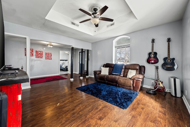 living room featuring a tray ceiling, ceiling fan, and dark hardwood / wood-style flooring