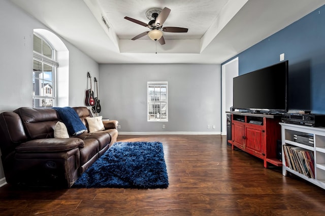 living room with a tray ceiling, ceiling fan, and dark hardwood / wood-style floors