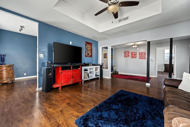 living room featuring dark hardwood / wood-style floors, ceiling fan, and a raised ceiling