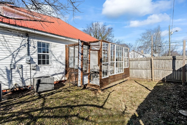 rear view of property featuring a lawn and central air condition unit