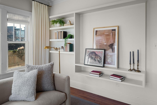 living area with hardwood / wood-style floors, ornamental molding, and built in shelves