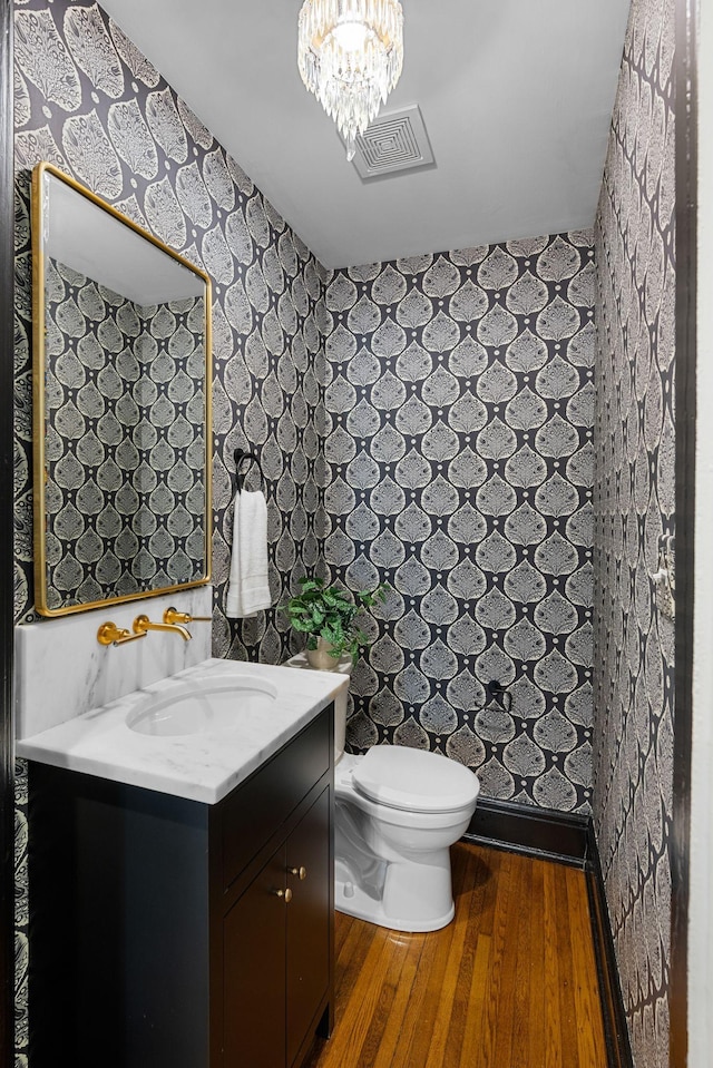 bathroom with vanity, hardwood / wood-style flooring, toilet, and an inviting chandelier