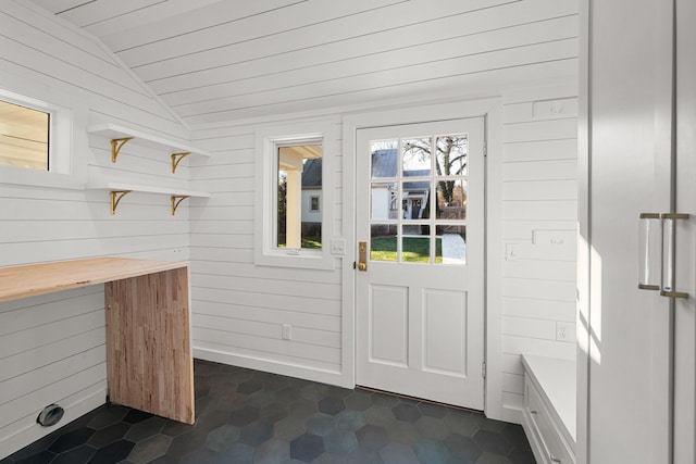 doorway to outside featuring wooden walls and lofted ceiling