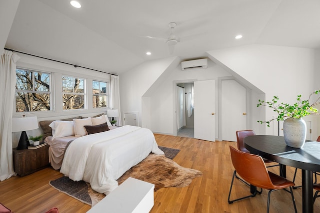 bedroom featuring ceiling fan, light wood-type flooring, an AC wall unit, and lofted ceiling