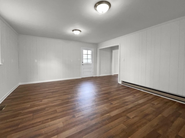 unfurnished room with dark hardwood / wood-style flooring, wooden walls, and a baseboard heating unit