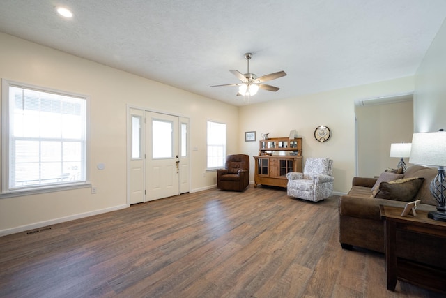 living room featuring ceiling fan and dark wood-type flooring