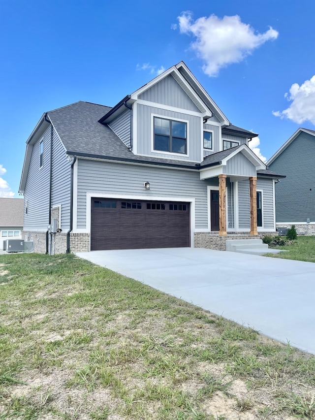 craftsman house with central AC unit, a garage, and a front lawn