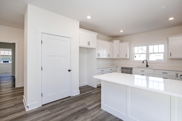 kitchen featuring a center island, dark wood-type flooring, sink, stainless steel dishwasher, and white cabinetry