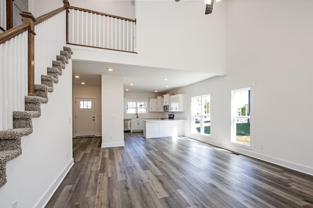 unfurnished living room with a towering ceiling, dark hardwood / wood-style floors, and sink