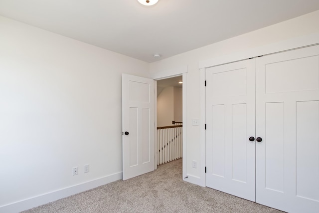 unfurnished bedroom featuring a closet and light colored carpet