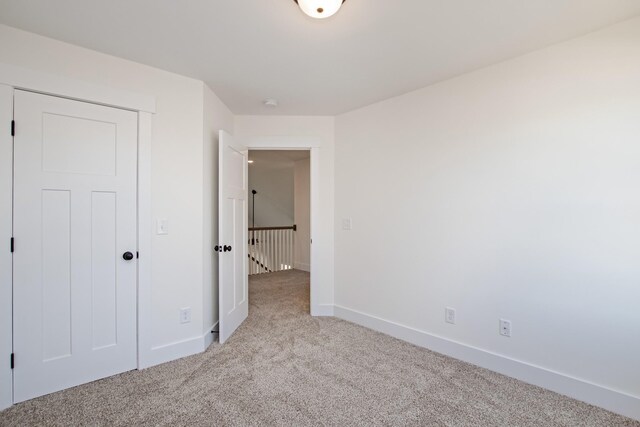 unfurnished bedroom with light colored carpet and a closet